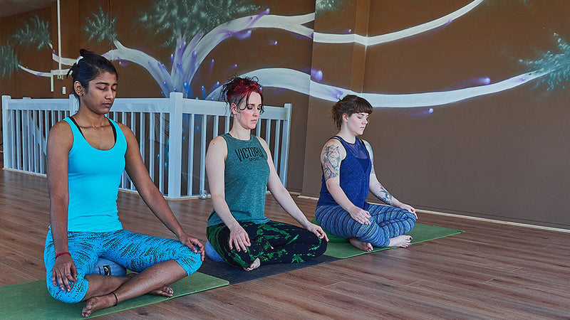 Three women meditating in a yoga studio